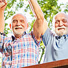 Ein Gruppe von Rentnerinnen und Rentnern streckt freudig die Arme in die Luft.