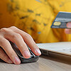 Frau sitzt am Laptop und kauft online mit Kreditkarte ein.