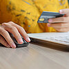 Frau sitzt am Laptop und kauft online mit Kreditkarte ein.