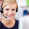 Lächelnde Beschäftigte eines Service Call Centers mit Headset