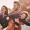 Familie geht bei herbstlichem Sonnenwetter am Strand spazieren