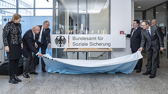 Hubertus Heil, Bundesminister für Arbeit und Soziales, Dr. Thomas Steffen, Staatssekretär im Bundesministerium für Gesundheit, Präsident Frank Plate, Vizepräsidentin Sylvia Bohlen-Schöning und der Bonner Bürgermeister Reinhard Limbach enthüllen das neue Namensschild des Bundesamtes für Soziale Sicherung.